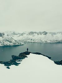 Scenic view of lake by snowcapped mountains against sky