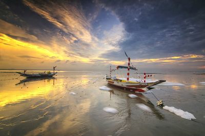 Boats moored on sea against sky during sunset