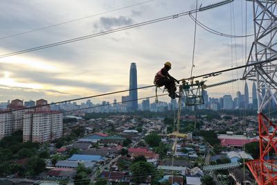 Man working on building in city against sky