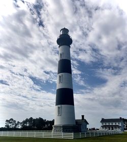 Low angle view of lighthouse by building against sky