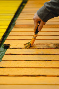 Close-up of person hand on yellow plank