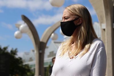 Portrait of woman standing outdoors while wearing a mask