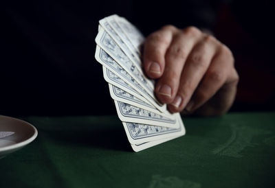 Close-up of hand holding cards at table