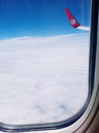 Airplane wing against sky seen through window