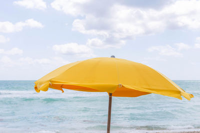 Yellow umbrella on beach against sky