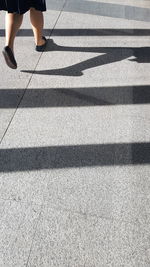 Low section of woman standing on zebra crossing