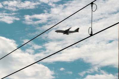 Low angle view of birds perching on cable against sky