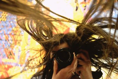 Woman with tousled hair photographing with camera