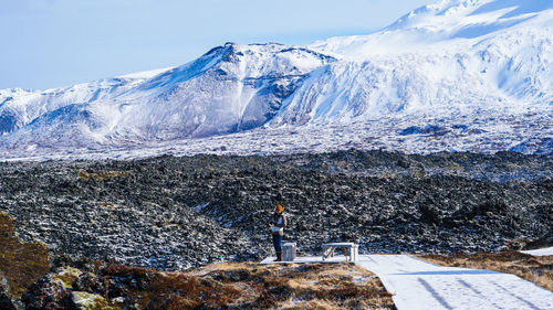 Woman standing on land against snowcapped mountain