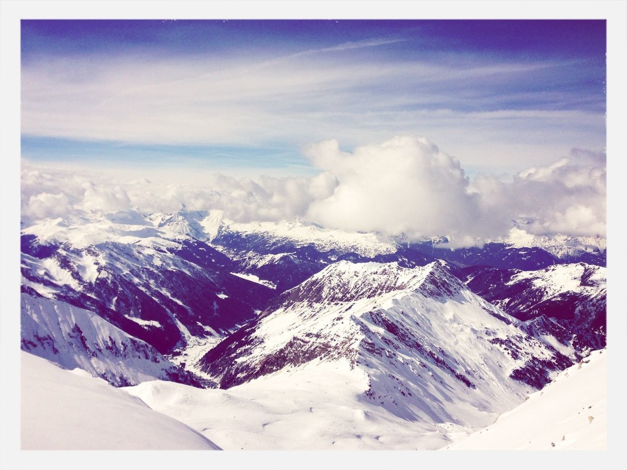 AERIAL VIEW OF SNOWCAPPED MOUNTAINS AGAINST SKY DURING WINTER