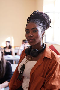 Portrait of confident female student with headphones in classroom
