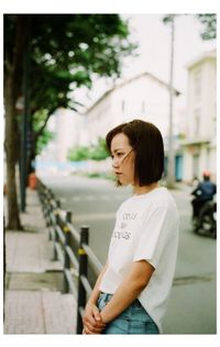 Side view of young woman standing against wall