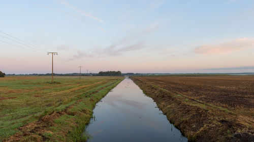 Scenic view of agricultural field against sky during sunset