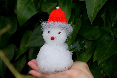 Close-up of hand holding  miniature snowman. 