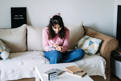 Young woman using laptop while sitting on sofa at home