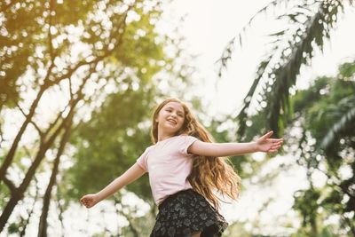 Portrait of smiling young woman standing against trees