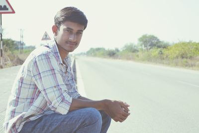 Portrait of young man sitting on road