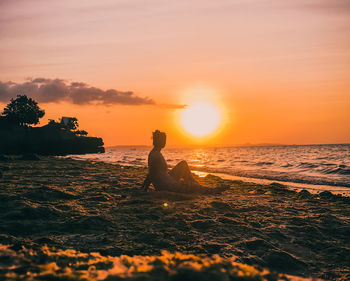 Silhouette person on beach against sky during sunset