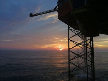 Silhouette built structure by sea against sky during sunset