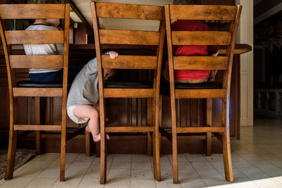 Toddler climbs down from tall chair in between two other children