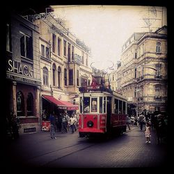 People on bus in city against sky