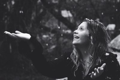 Close-up of cheerful woman looking up during snowfall