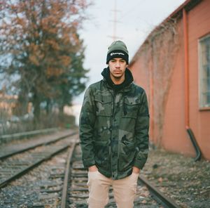 Portrait of young man standing on railroad track