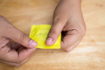 Close-up of man holding condom on table