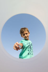 Low angle view portrait of boy holding battery