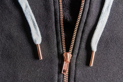 Copper colored fashion zipper in close-up macro view showing black sweatshirt with opened zipper