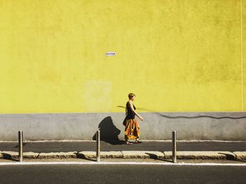 Full length of woman sitting on yellow road