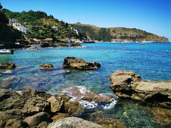 Scenic view of rocks in sea against blue sky