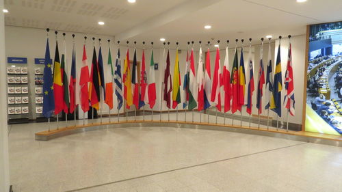 Multi colored flags hanging on tiled floor against wall