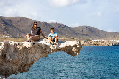 Woman and kid on a rock of playa del arco, almeria, spain