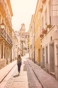 Rear view of woman walking on street amidst buildings