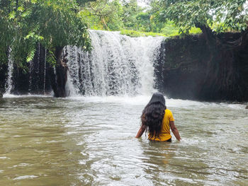 Rear view of man standing in waterfall