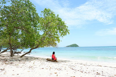 People sitting on beach by sea against sky