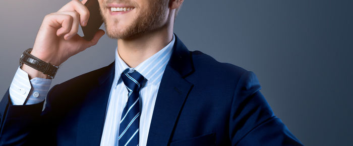 Midsection of man using mobile phone against blue sky