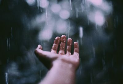 Cropped hand of person holding water during rainy season