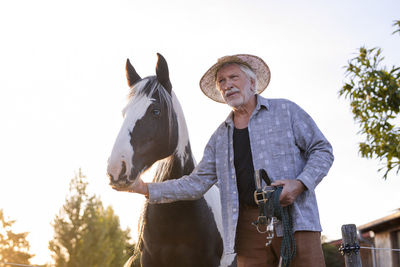 Farmer standing with horse at farm