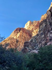 Low angle view of rocky mountain against blue sky