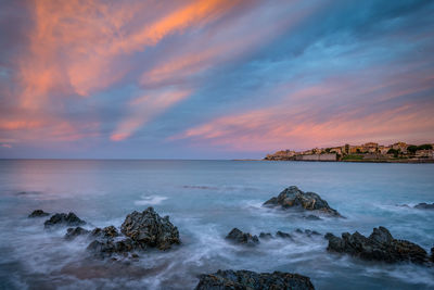 Scenic view of sea against cloudy sky during sunset