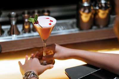 Cropped hand of woman holding drink on table