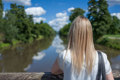 Rear view of woman standing on bridge over river