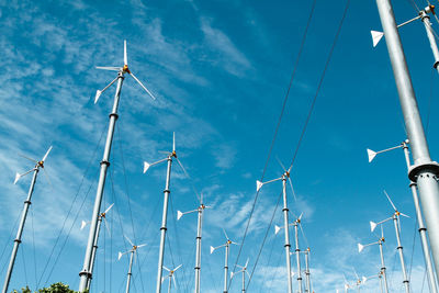 Low angle view of windmills against blue sky