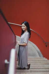 Side view portrait of young woman standing on steps