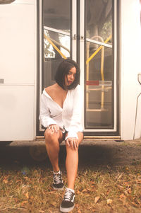 Full length portrait of woman standing against door