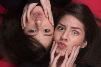 Portrait of young women lying over red background