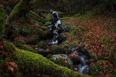 Man walking over stream in forest during autumn