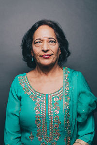 Portrait of confident senior woman wearing salwar kameez on gray background